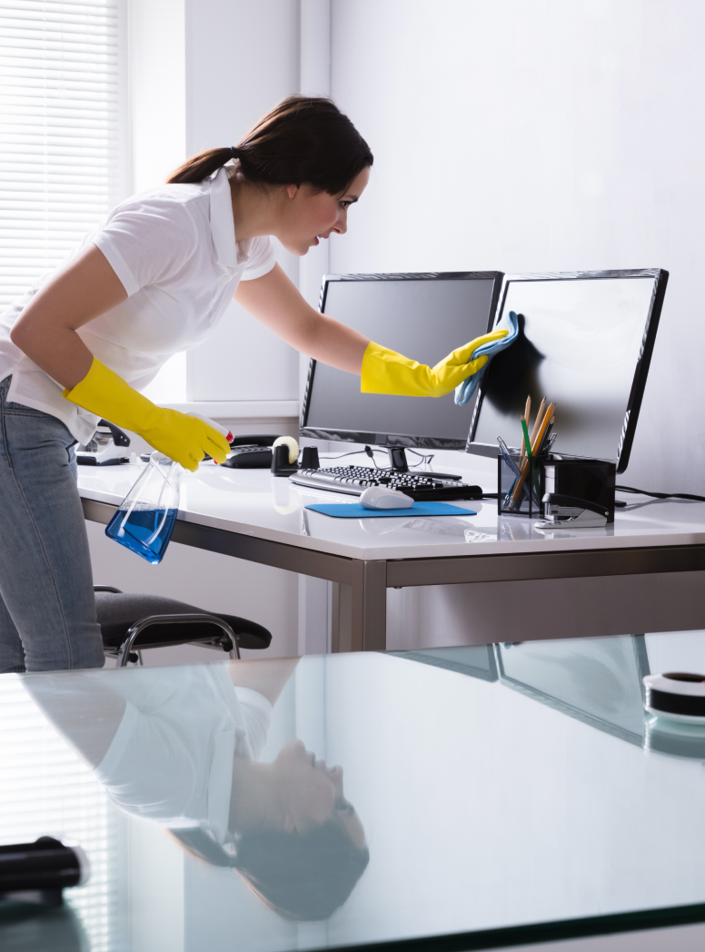 Commercial cleaner in Washington DC, Virginia, and Maryland wearing yellow gloves and using a blue microfiber cloth to wipe computer screen at an office